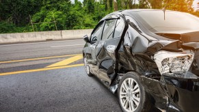 Black car in left rear angle smashed down the side after a car accident likely total loss Progressive insurance settled a total loss value underpayment lawsuit in July 2024