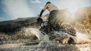 A 2024 Harley-Davidson Pan America 1250 Special ADV motorcycle kicks up water.