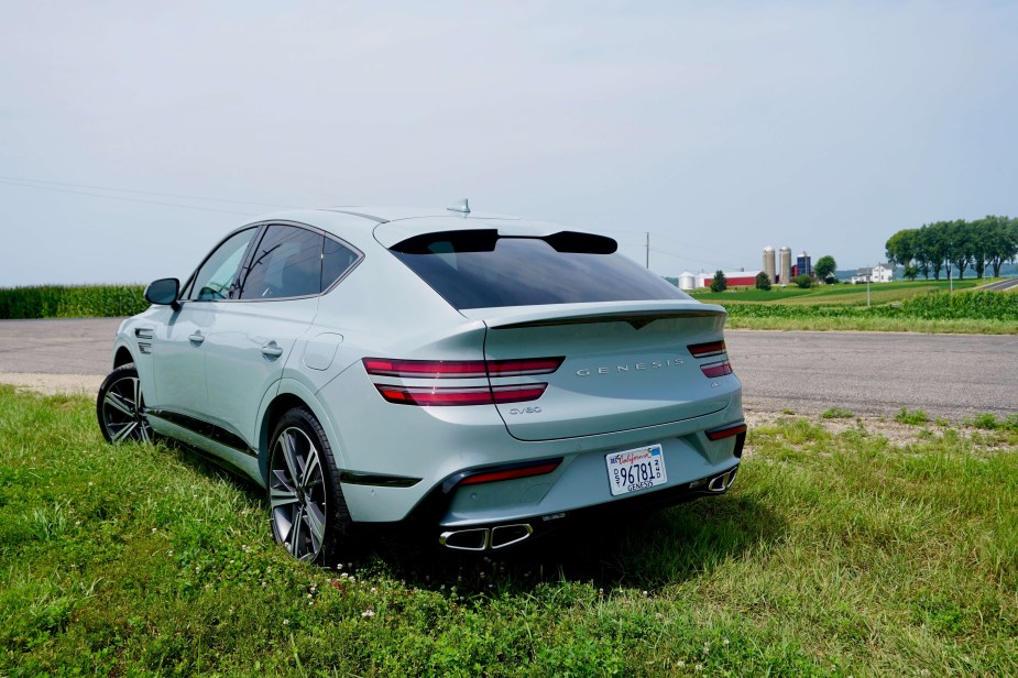 The rear of a gray Genesis crossover SUV parked in a field