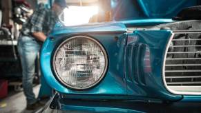 An owner works on an old, classic car in their shop.