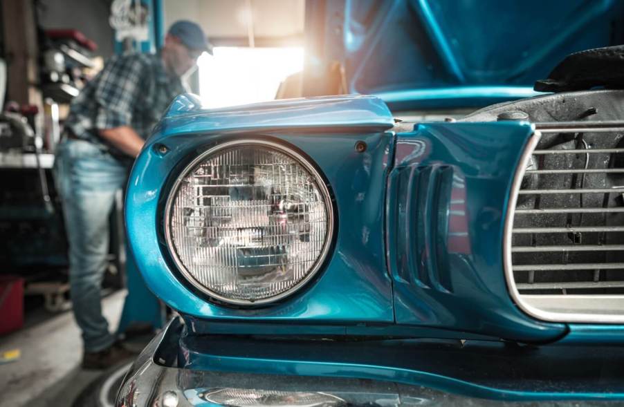 An owner works on an old, classic car in their shop.