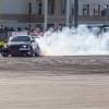 A Nissan drift car slides in a cloud of smoke in front of spectators.