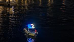 A police boat lights up the waters in a harbor.