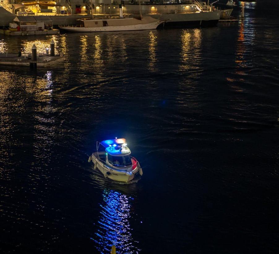 A police boat lights up the waters in a harbor.