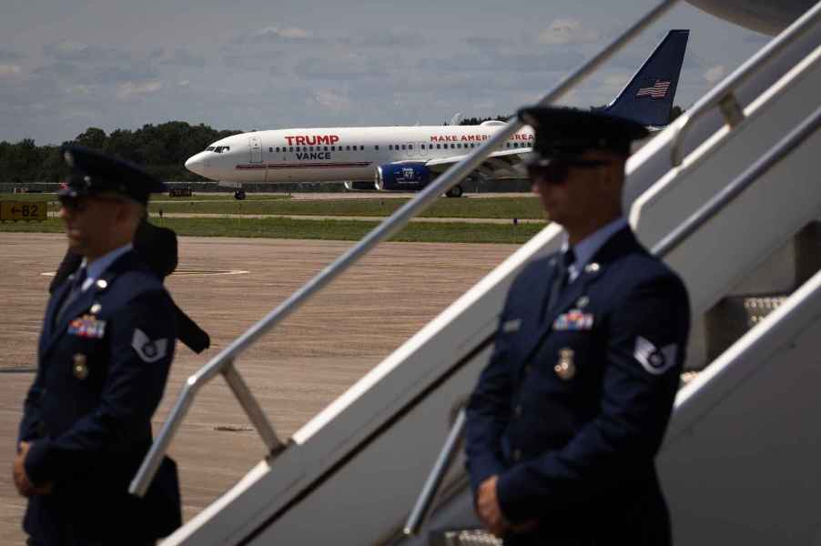 A view of Trump and Vance campaign plane as it taxis on Wisconsin tarmac with Air Force Two stairs and Secret Service agents in blurred foreground