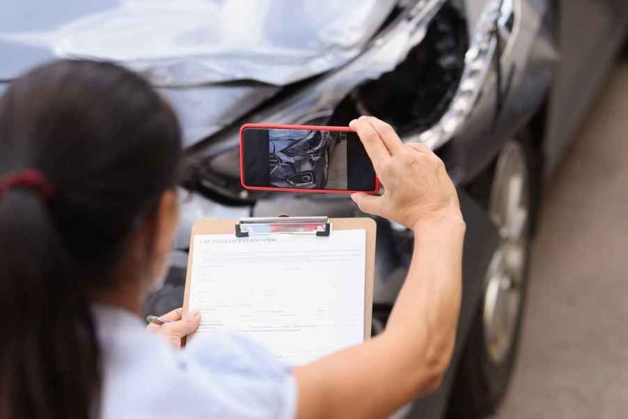 A car insurance rep takes photos of collision damage