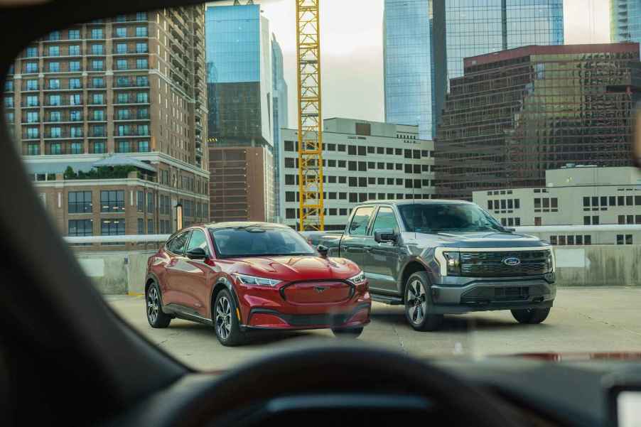 Two Ford EV models, F-150 Lightning and Mustang Mach-E, parked on a city building rooftop in right front view