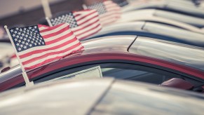 A row of cars in very close view with American flags in the windows parked at a car dealership