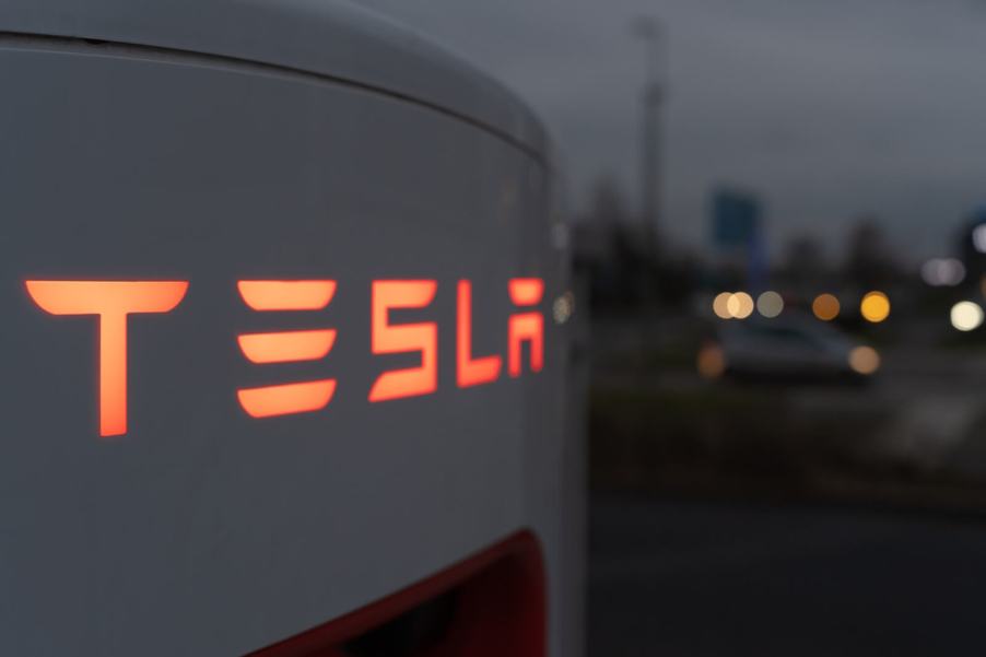 A Tesla charger, like the ones that could charge the Tesla Robotaxi, is illuminated in the dark.