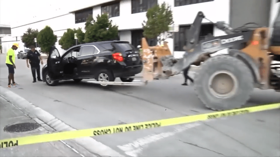 A construction working using a forklift to move an SUV