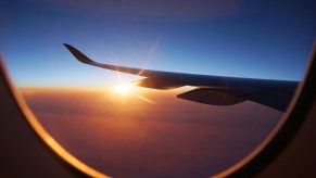 Window of a commercial jet airliner, the sunset visible in the background.