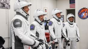 Four international and NASA astronauts who were the ISS crew for 200 days smile while suiting up.