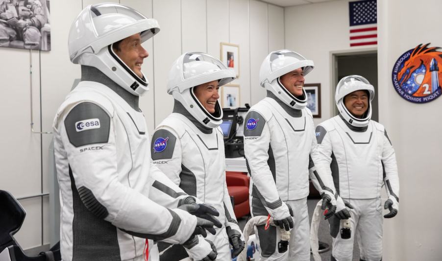 Four international and NASA astronauts who were the ISS crew for 200 days smile while suiting up.