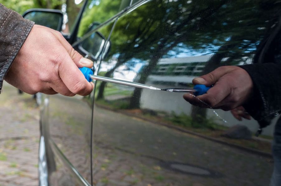 A car is vandalized with a screwdriver.