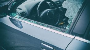 A criminal vandalizing a car smashes the driver's side windows.