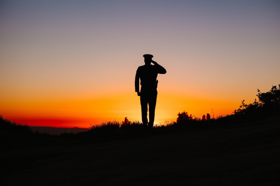 Police officer standing in front of the setting sun.