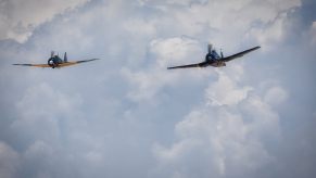 WWII airplanes fly next to one another in a color image.