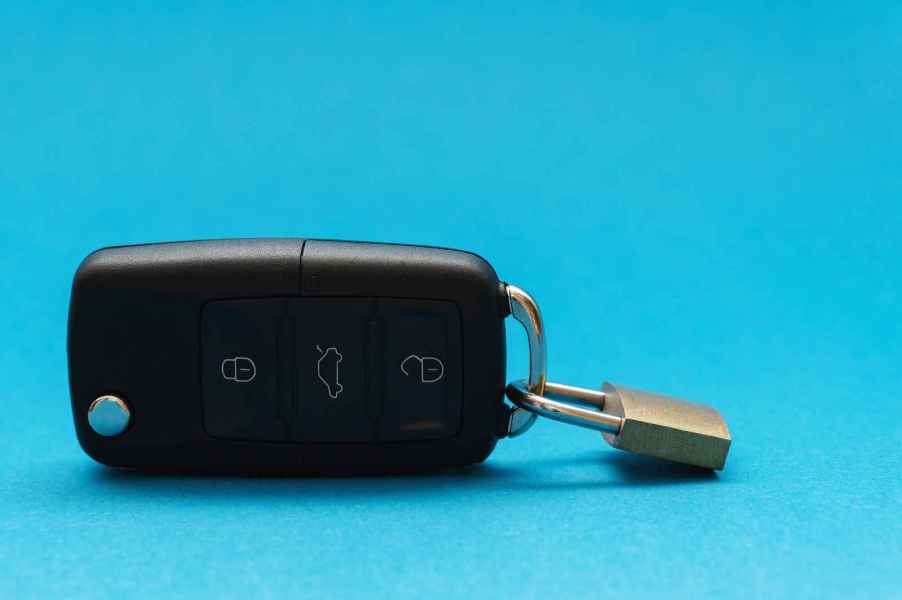 Car key fob with tiny padlock latched on depiction of a car loan