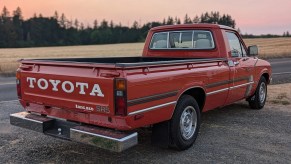 A red 1980 Toyota SR5 Pickup truck parked in right rear angle view with the sun setting in background