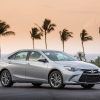 A silver 2017 Toyota Camry parked in front of tall palm trees at dusk