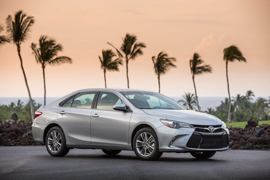 A silver 2017 Toyota Camry parked in front of tall palm trees at dusk