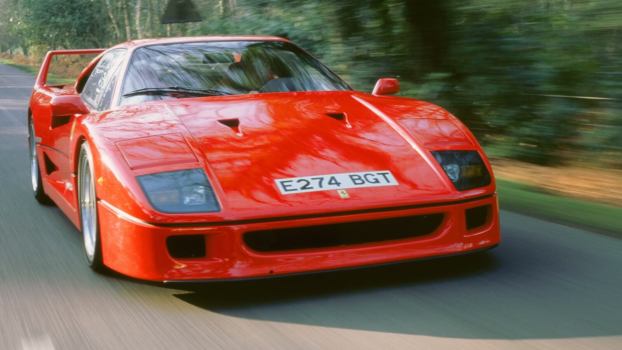 A 1988 Ferrari F40, a benchmark among old supercars, barrels down a straight road.