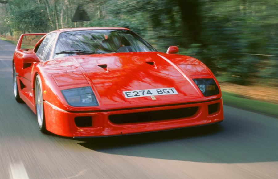 A 1988 Ferrari F40, a benchmark among old supercars, barrels down a straight road.