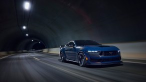 A Ford Mustang Dark Horse drives through a dark tunnel.