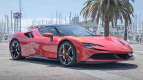 A red Ferrari SF90 Stradale parked at a marina in right front angle view