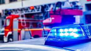 Police cruiser lights in close view positioned in front of a fire truck in the background