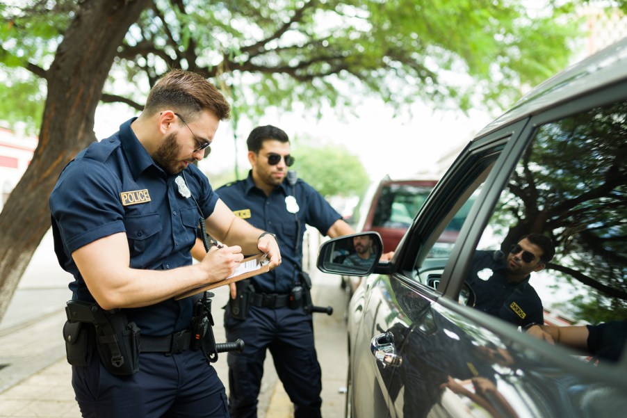 Two police officers writing a ticket at a traffic stop