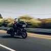 Man riding a motorcycle fast on US road in right front and side angle view with power lines and trees blurred in background