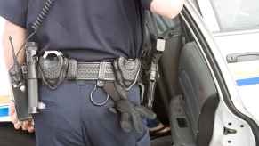 A police officer making an arrest putting someone in cruiser view of officer's back in front of open right rear door