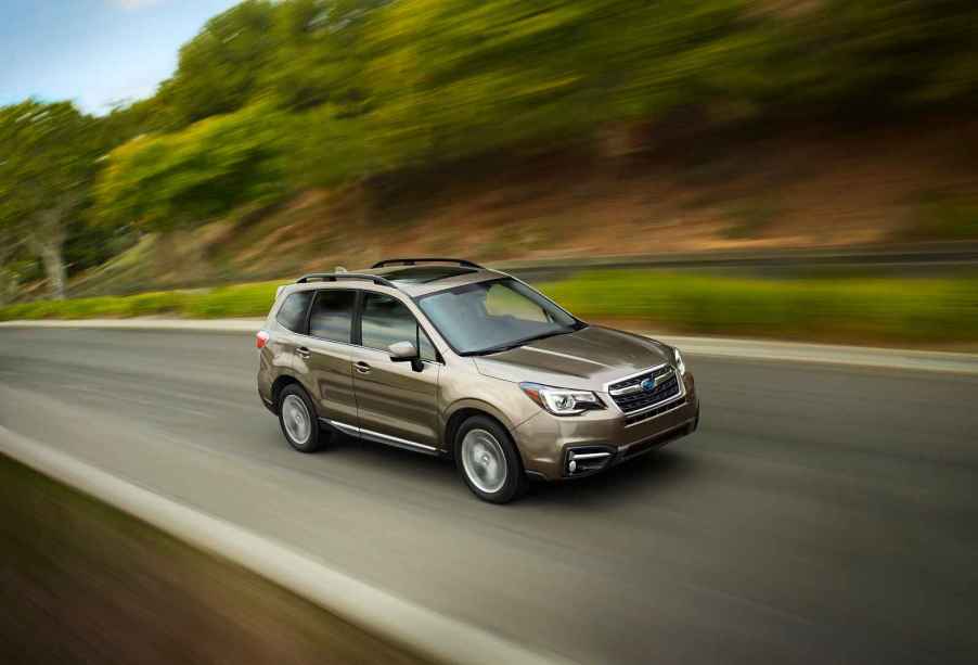 A metallic 2017 Subaru Forester driving on a hilly highway in right front angle view