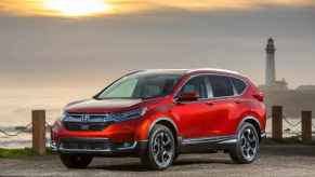 A red 2018 Honda CR-V parked in front of water and lighthouse