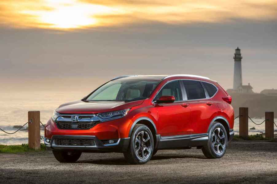 A red 2018 Honda CR-V parked in front of water and lighthouse