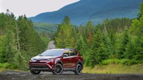 A red 2018 Toyota RAV4 parked on a road in the wilderness in left front angle view