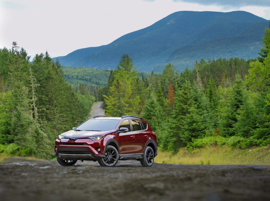 A red 2018 Toyota RAV4 parked on a road in the wilderness in left front angle view