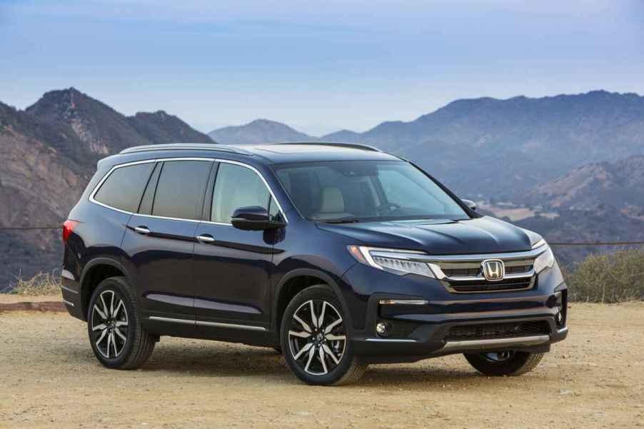 A dark blue 2019 Honda Pilot Elite parked in right front angle view in front of mountain range