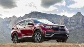 A dark red 2020 Honda CR-V Hybrid parked on a grassy mountainous hilltop