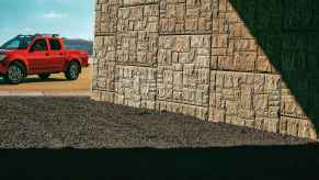 A red 2020 Nissan Frontier parked in background with stone wall in foreground