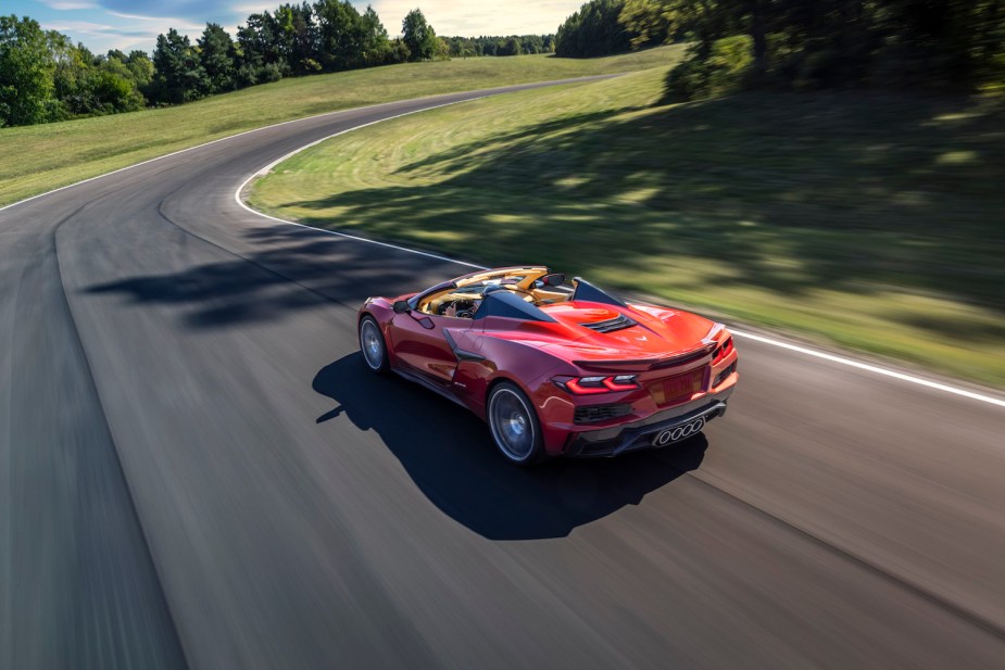 Red Chevrolet Corvette Z06 supercar with its top down driving on a country road.