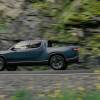 A Rivian R1T pickup truck driving on a road.