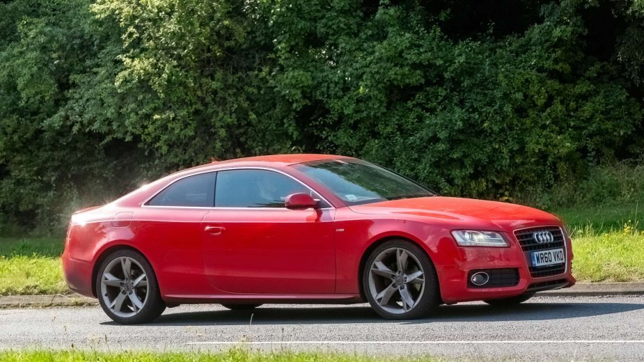 Red Audi Sportback coupe driving on a country road.