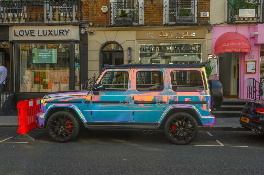 Shiny, chrome-plated G Wagon SUV parked outside a luxury store on a London street.