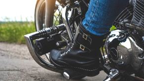 Black leather boots of a motorcyclist, on the bike's pegs