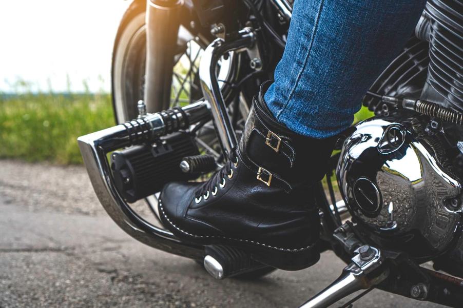 Black leather boots of a motorcyclist, on the bike's pegs