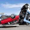 Overturned car transport truck on the highway, a crashed exotic car visible in the foreground.