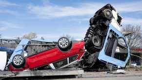 Overturned car transport truck on the highway, a crashed exotic car visible in the foreground.