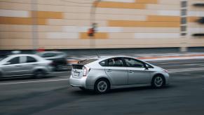 A driver in a third-generation Toyota Prius drives quickly on a city street.